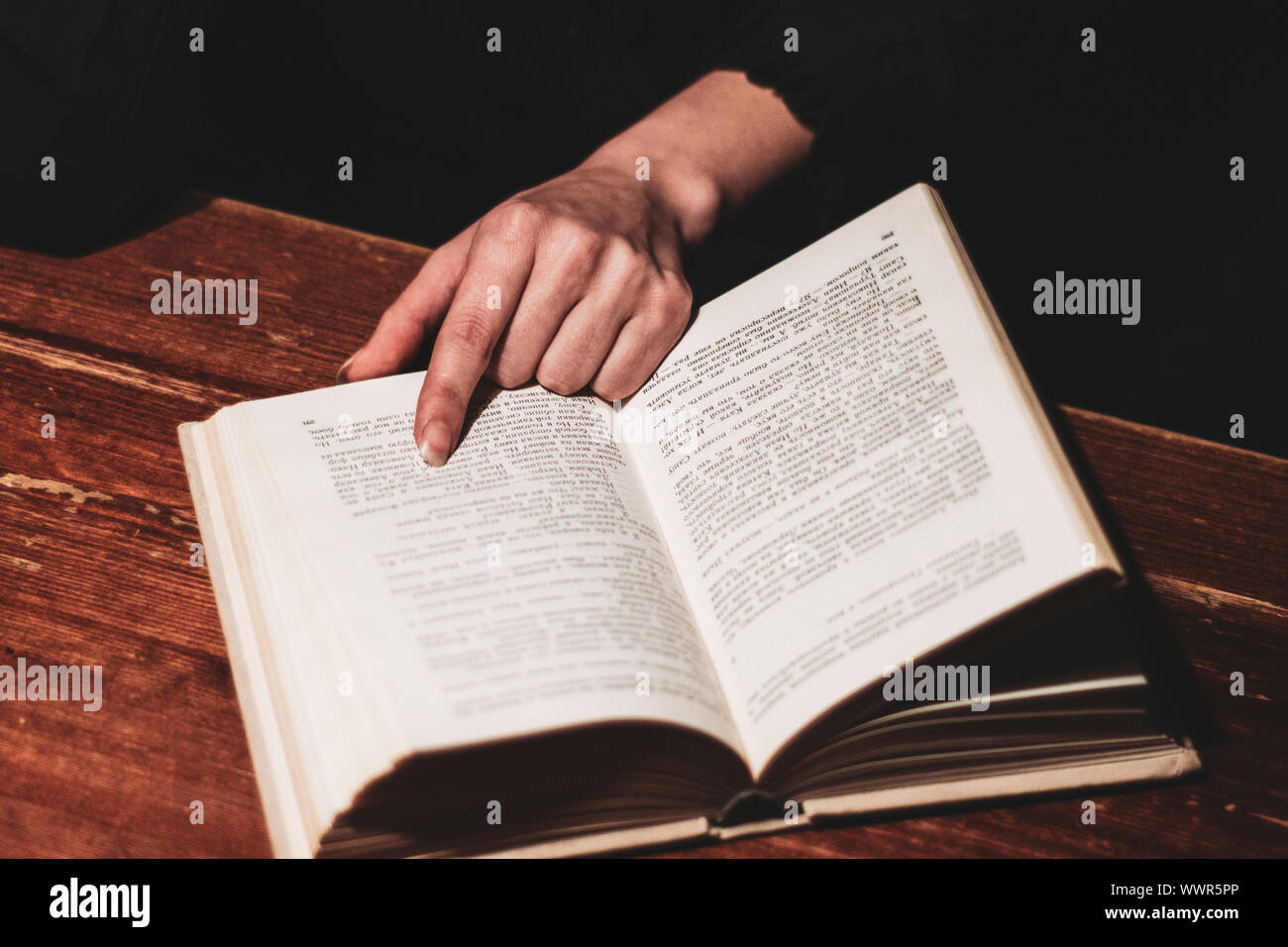 Frau Hand buch auf hölzernen Tisch Stockfoto