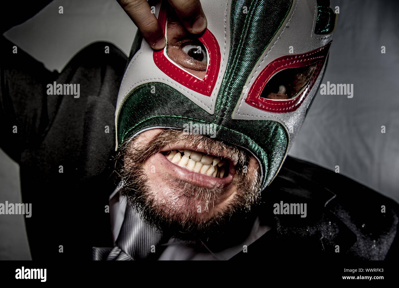 Wütend Geschäftsmann mit Maske des mexikanischen Kämpfer, gekleidet in Anzug und Krawatte Stockfoto