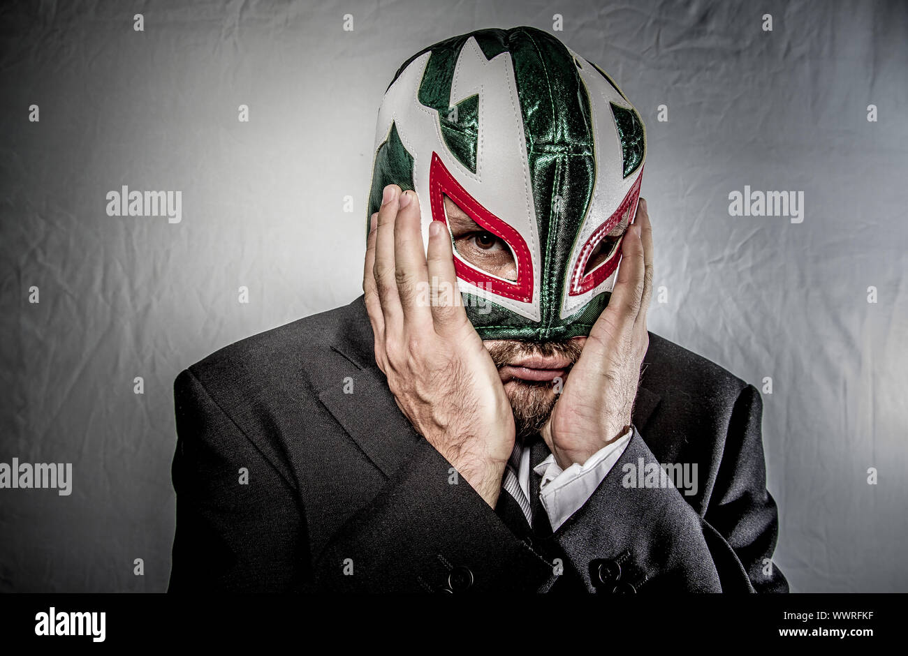 Stress, wütend Geschäftsmann mit Maske des mexikanischen Kämpfer, gekleidet in Anzug und Krawatte Stockfoto