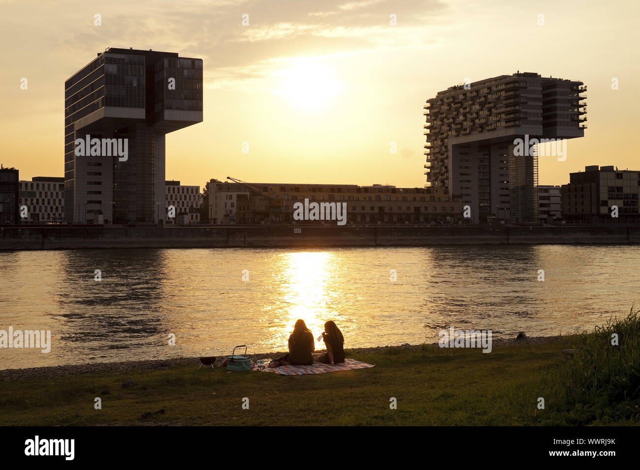 Zwei Personen am Rhein mit zwei Kranhaeuser bei Sonnenuntergang, Köln, Deutschland, Europa Stockfoto
