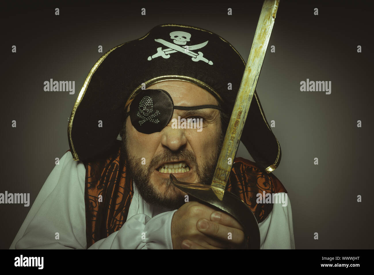 Mann mit Bart, gekleidet wie ein Pirat mit Augenklappe und Stahl Schwert Stockfoto