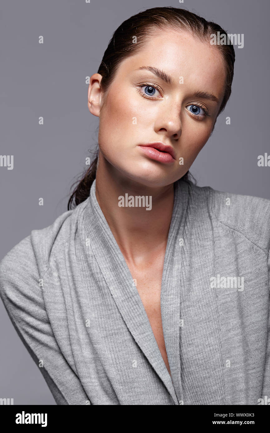 Schönheit Porträt der jungen Frau im grauen Kleid. Brünette Mädchen mit hellen blauen Augen und Tag weibliche Make-up Stockfoto