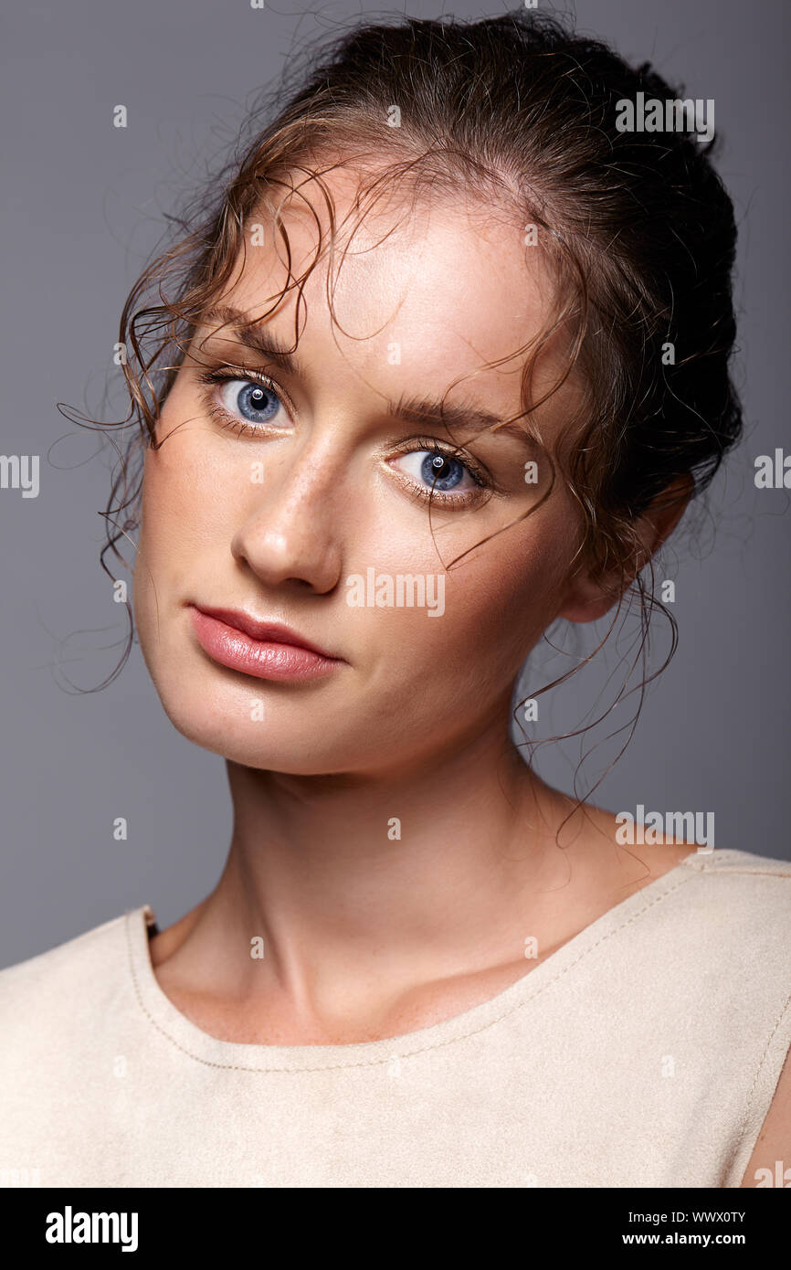 Schönheit Porträt der jungen Frau. Brünette Mädchen mit hellen blauen Augen und Tag weibliche Make-up auf grauem Hintergrund Stockfoto