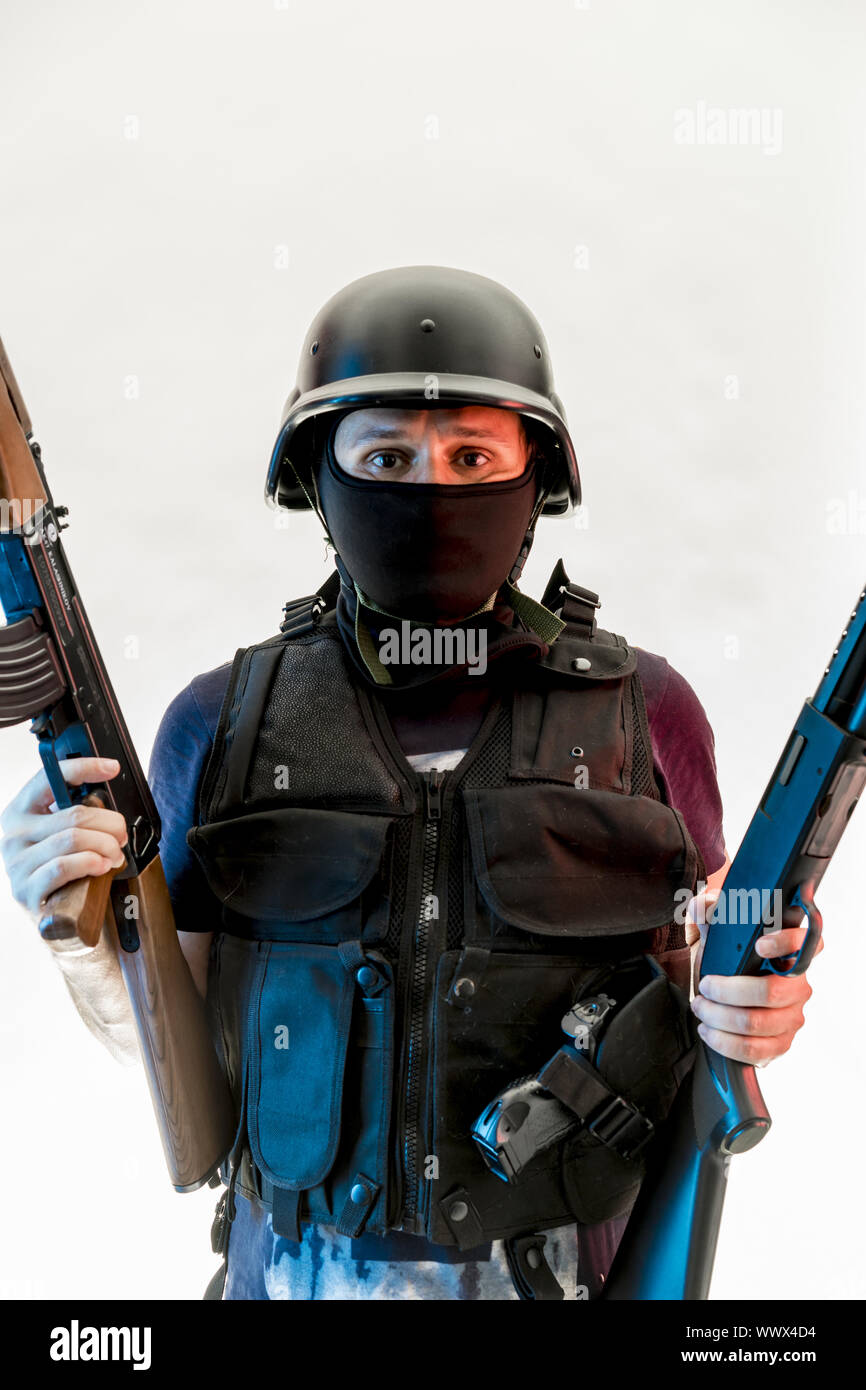 Bewaffneter Mann mit Sturmhaube und kugelsichere Weste, Pistole und Schrotflinte, kalaschnikow Stockfoto