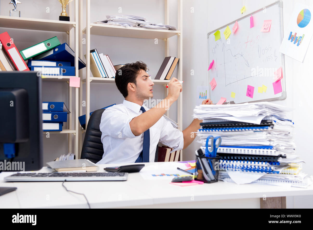 Unternehmer, die im Büro mit Stapel von Büchern und Zeitschriften Stockfoto