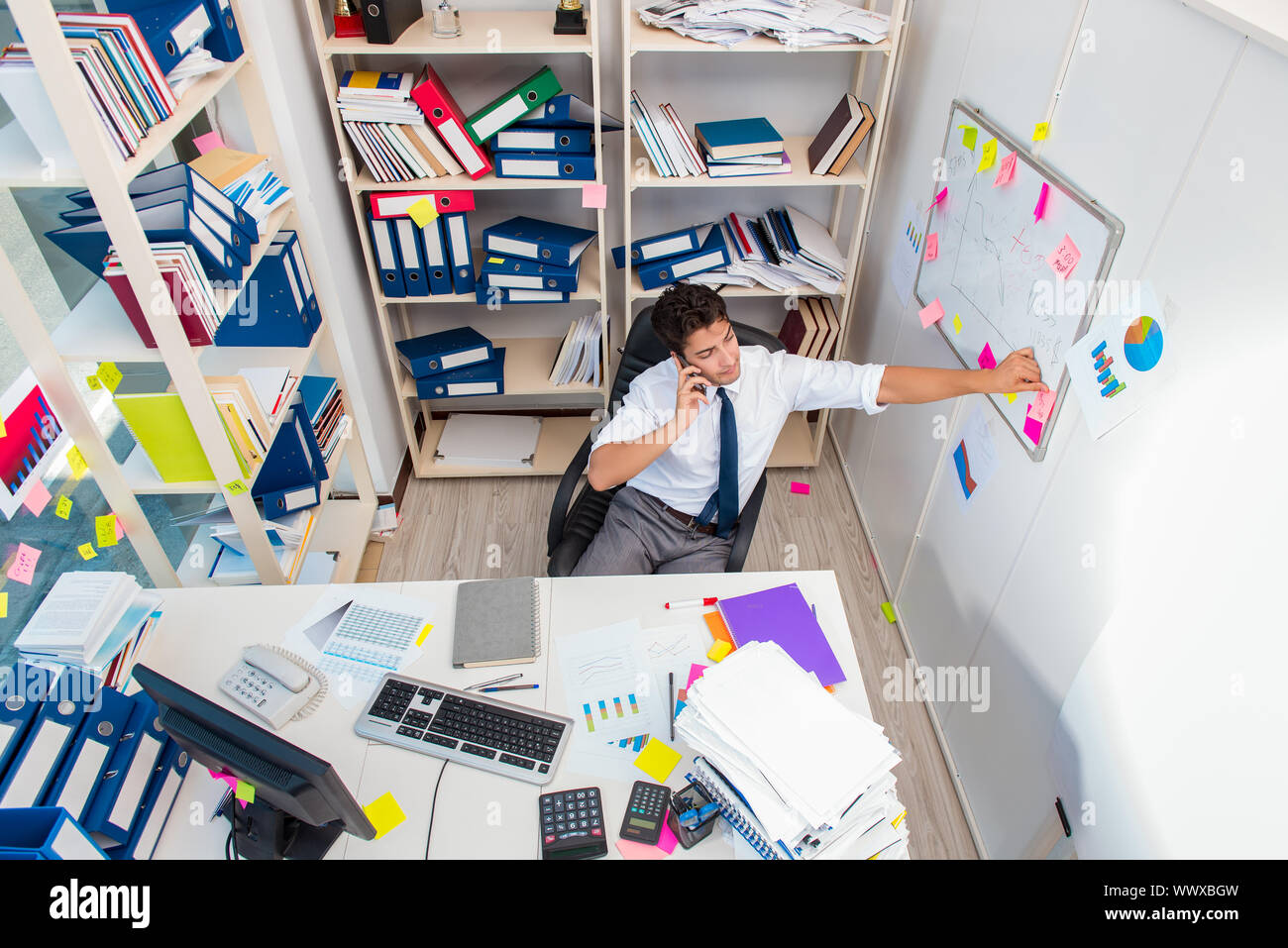 Unternehmer, die im Büro mit Stapel von Büchern und Zeitschriften Stockfoto