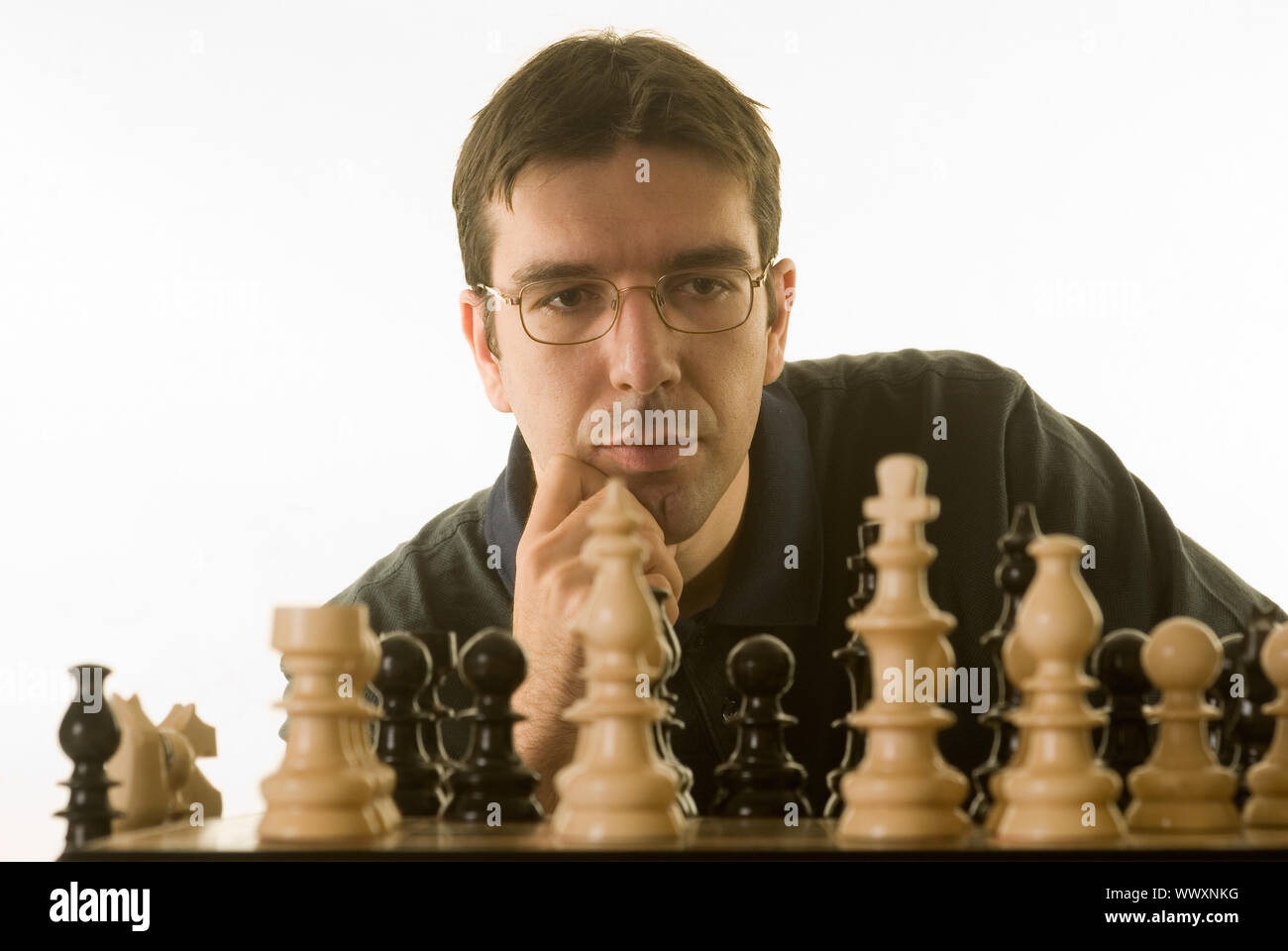 junger Mann spielt Schach gegen einen weißen Hintergrund isoliert Stockfoto