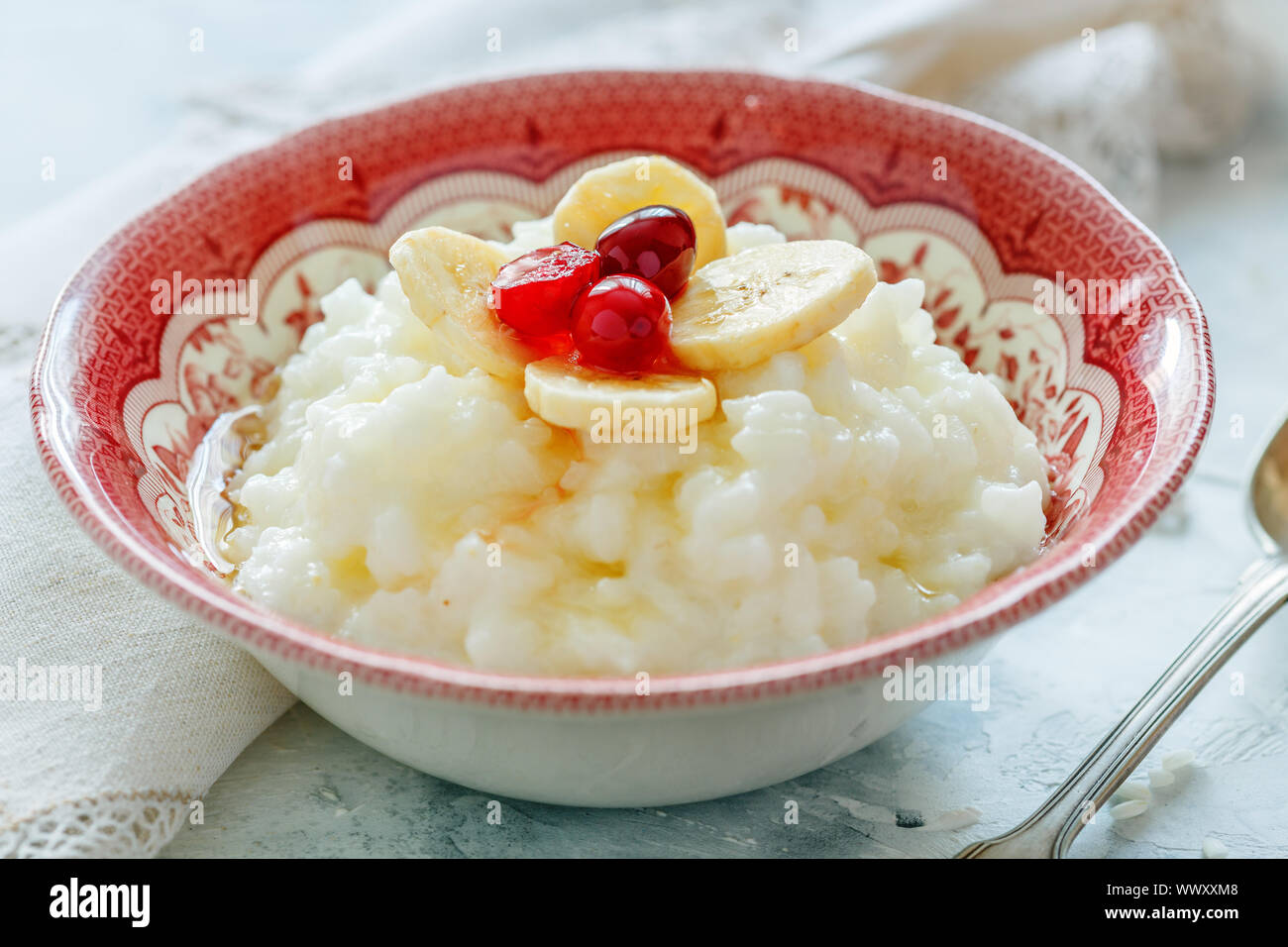Schüssel mit Milch Reisbrei, Bananen, Beeren und Honig. Stockfoto