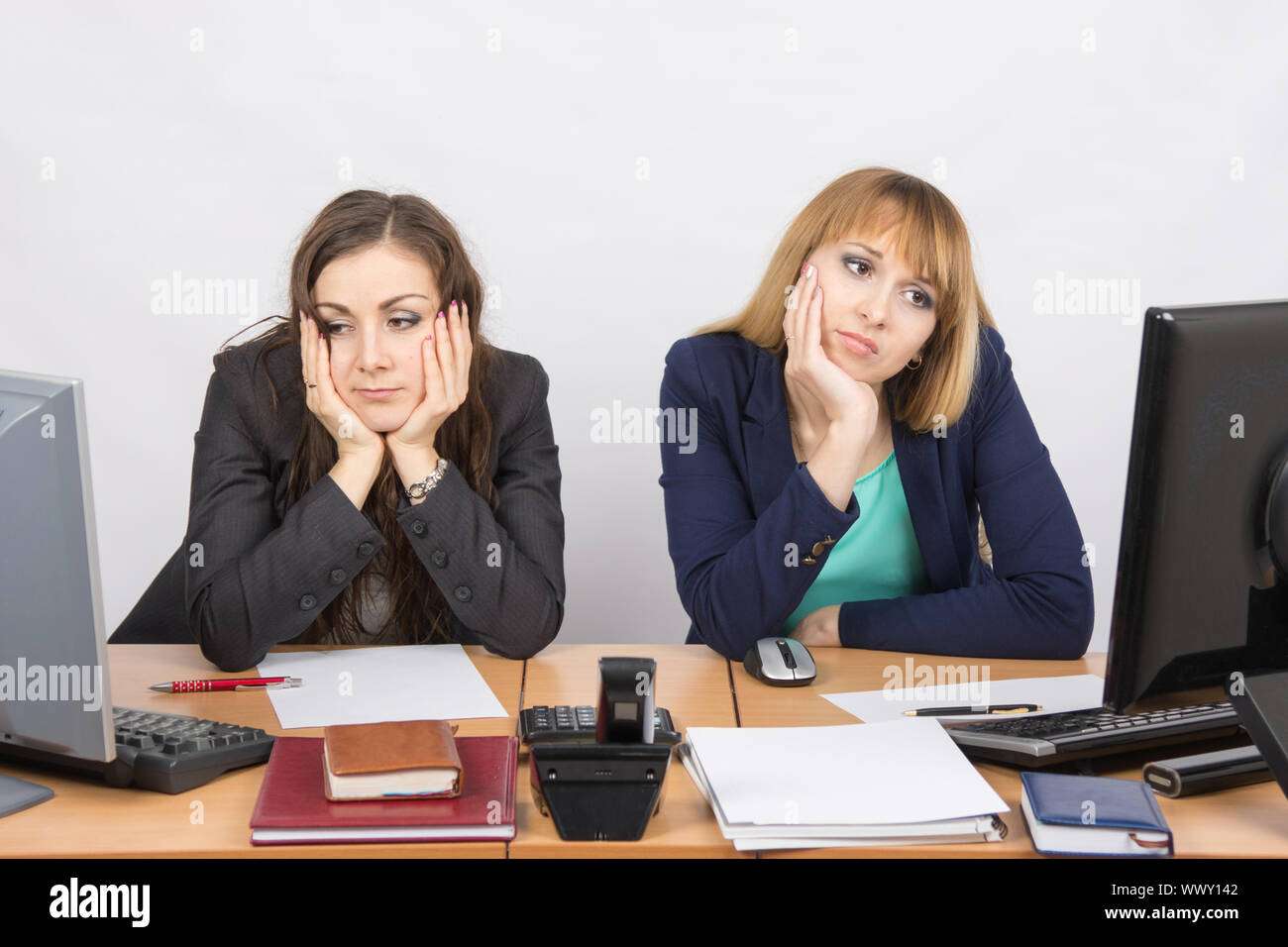 Zwei junge Büroangestellte müde vor Computern sitzen Stockfoto