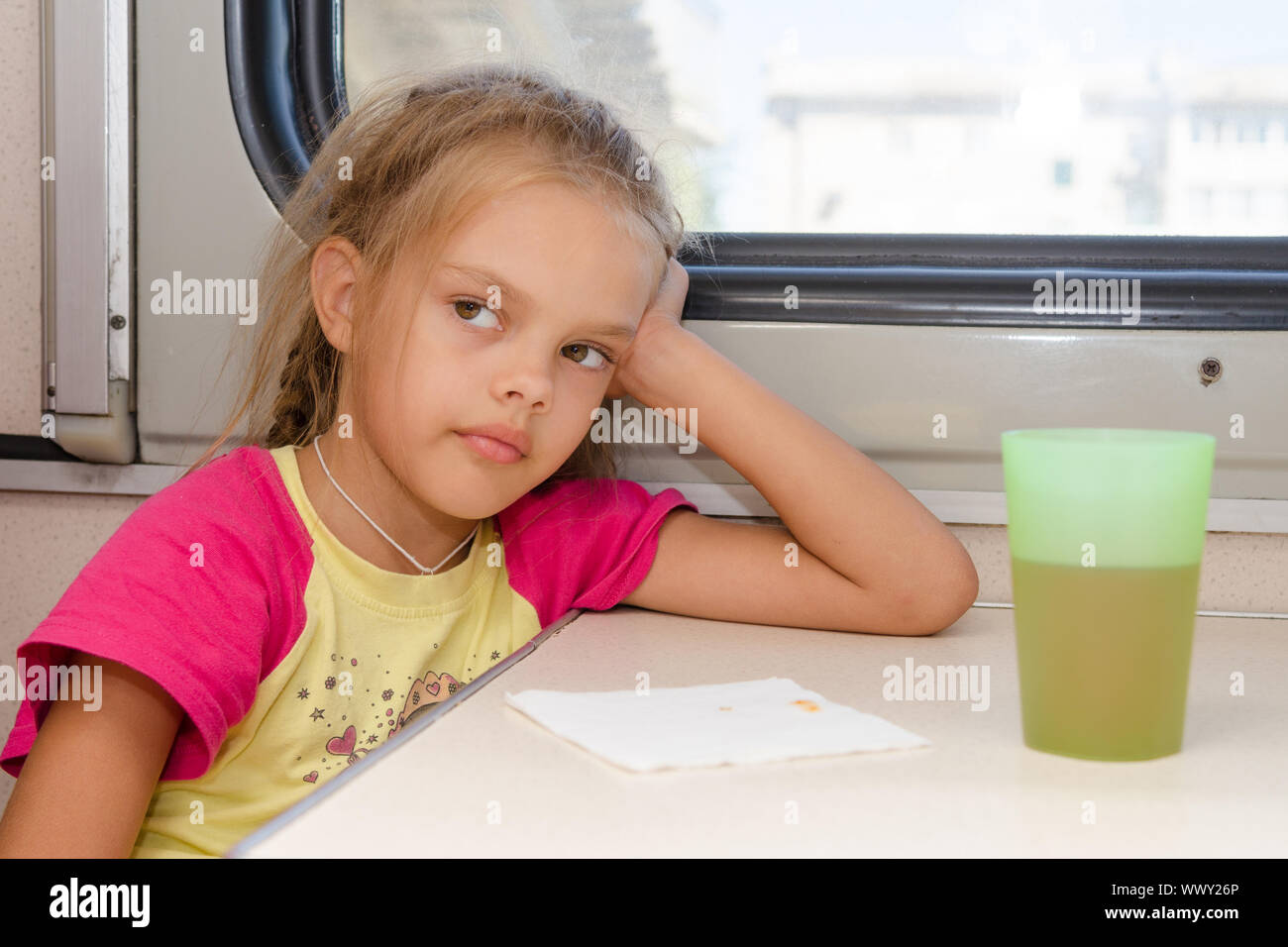 Sechsjährigen Mädchen nachdenklich und müde sitzen im Zug auf dem Tisch im Abteil zweiter Klasse Stockfoto