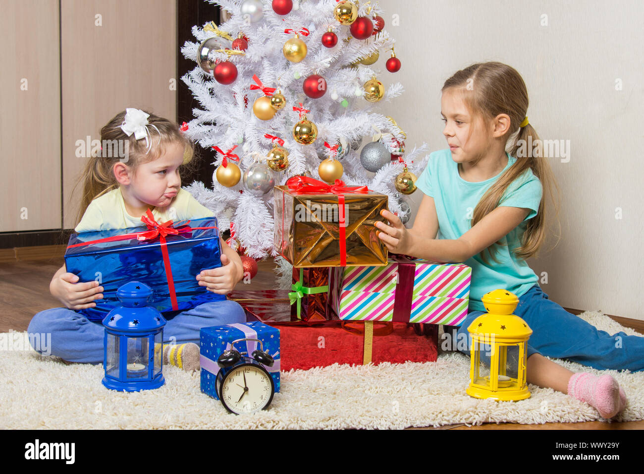 Zwei Mädchen teilen präsentiert Neujahr Geschenke am Weihnachtsbaum Stockfoto
