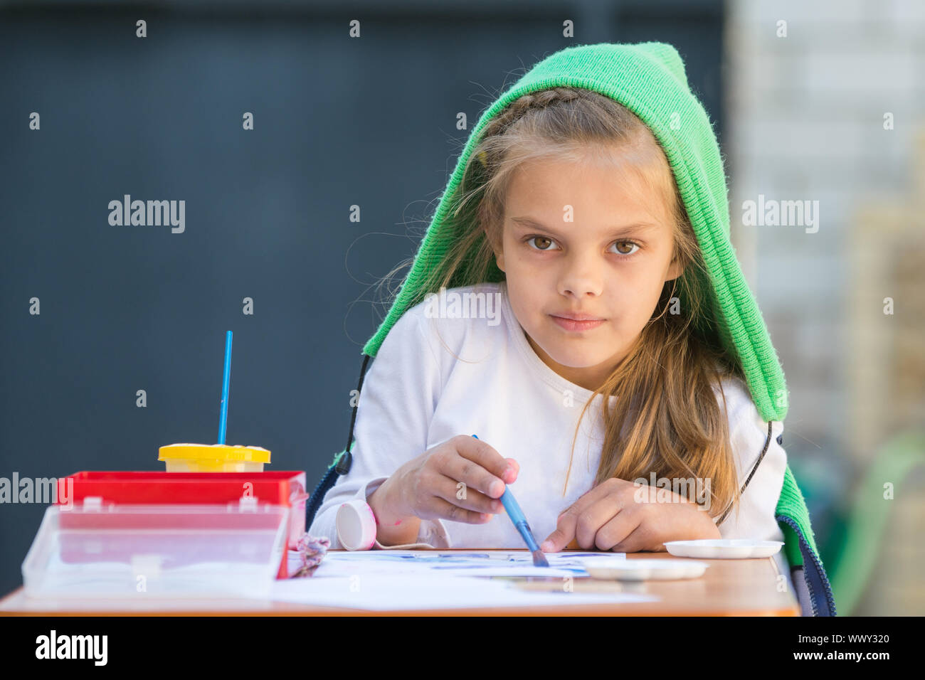 Zufrieden Mädchen zieht Farben am Tisch und schaute auf den Rahmen Stockfoto