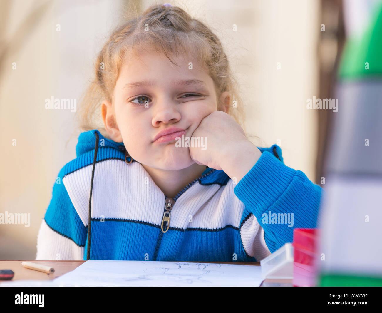 Trauriges Mädchen dachte dabei an einem Tisch im Hof zeichnen Stockfoto