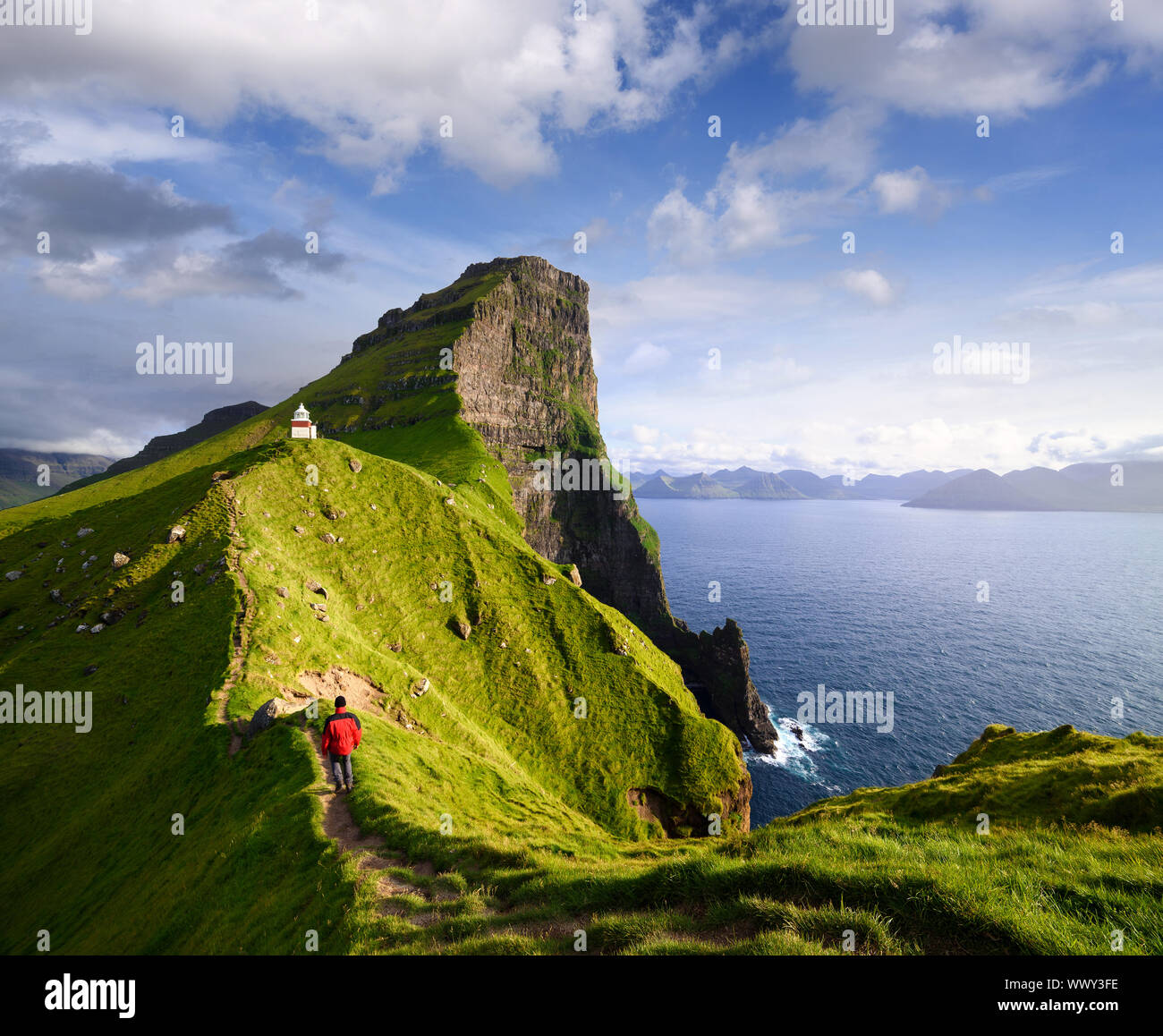 Kallur Leuchtturm auf der Insel Kalsoy. Wandern auf den Färöer Inseln. Touristen in eine rote Jacke der Besuch einer Touristenattraktion. Sommer Bergwelt Stockfoto