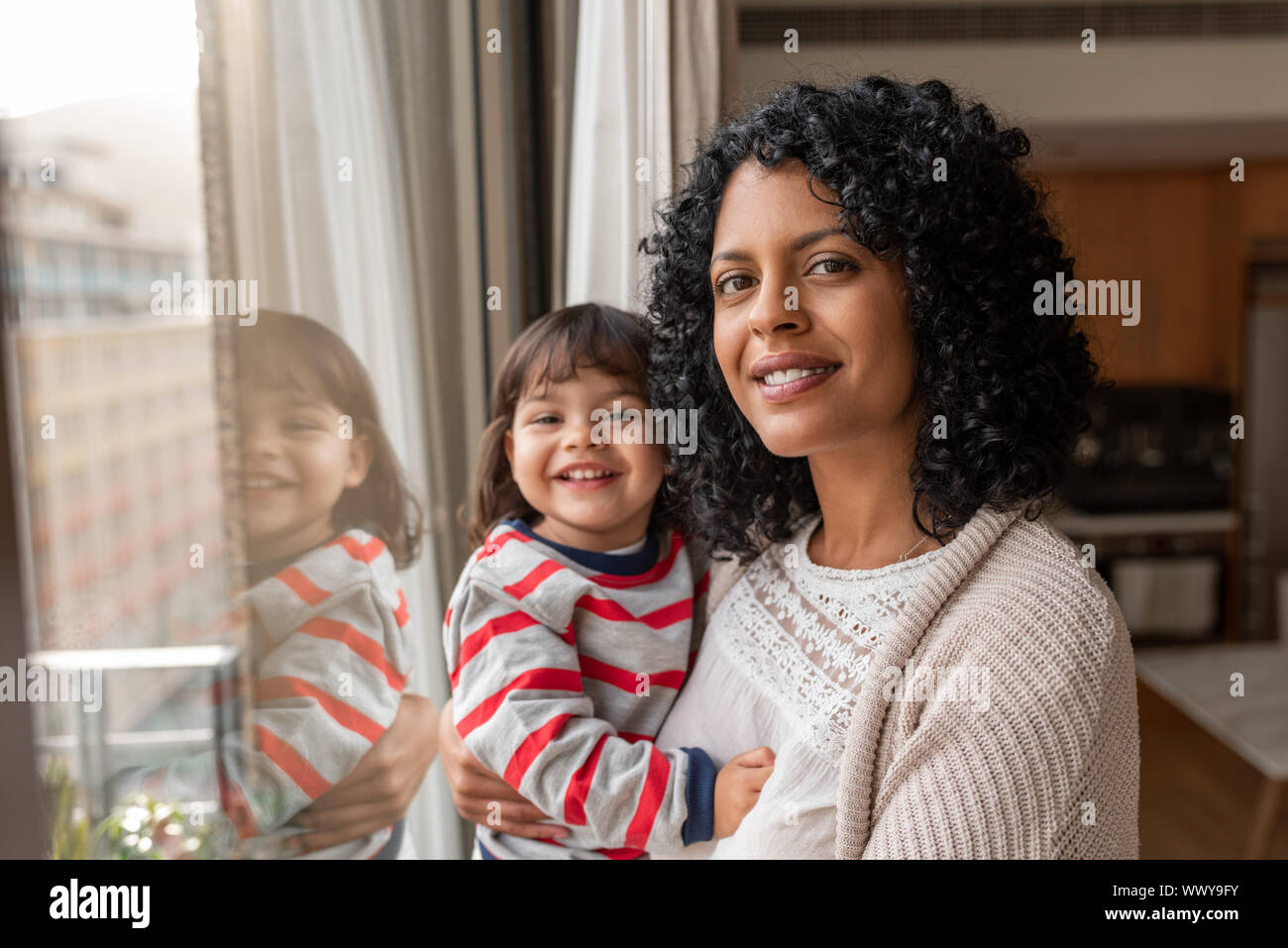 Lächelnde Mutter und Tochter ihre Wohnzimmer Fenster Stockfoto