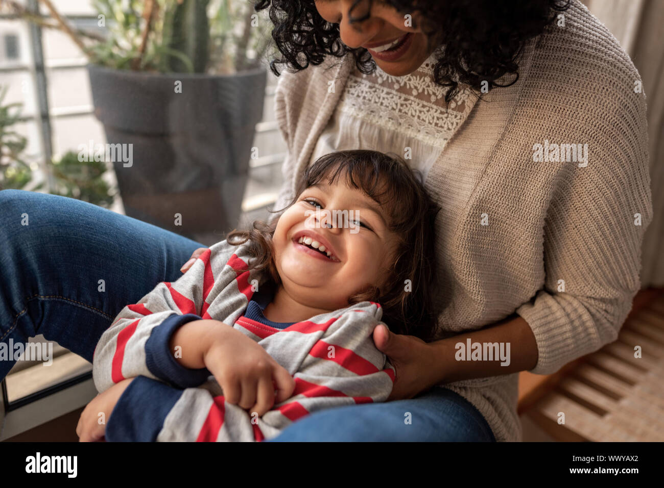 Lächelnde Mutter und Tochter zusammen zu Hause spielen Stockfoto