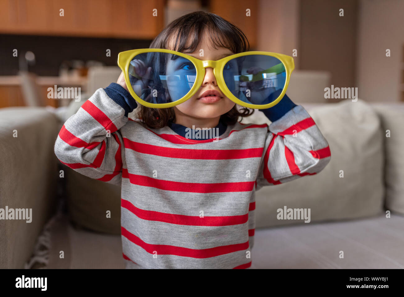 Süße kleine Mädchen spielen mit übergroßen Neuheit Sonnenbrille zu Hause Stockfoto