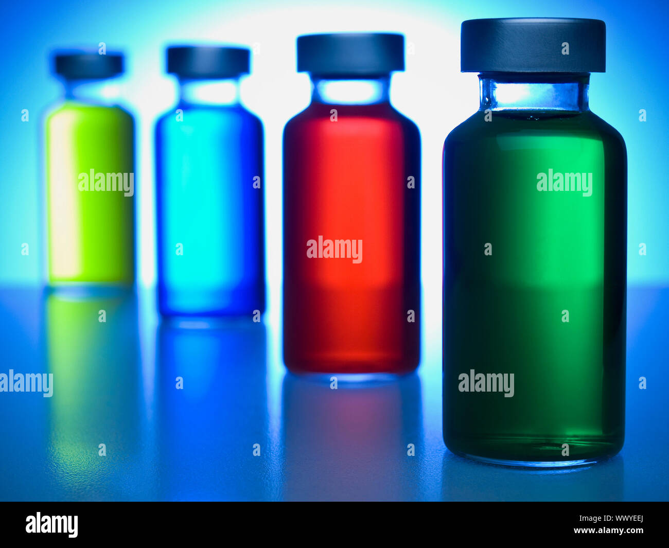 Eine Reihe von Fläschchen gefüllt mit farbigen Flüssigkeiten. Konzentrieren Sie sich auf grün. Stockfoto