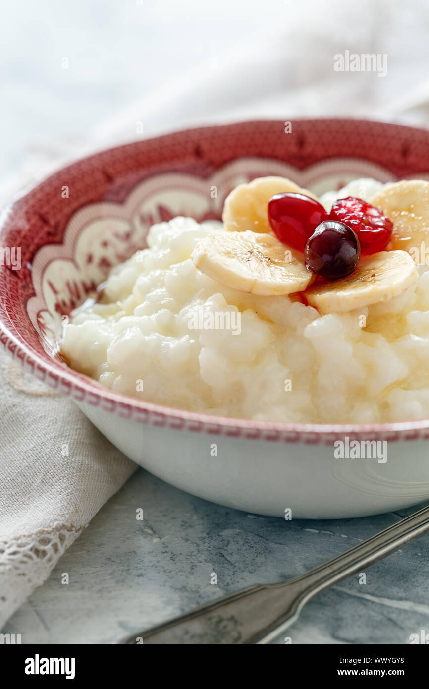 Schüssel mit Milch Reisbrei, Bananen, Beeren und Honig. Stockfoto