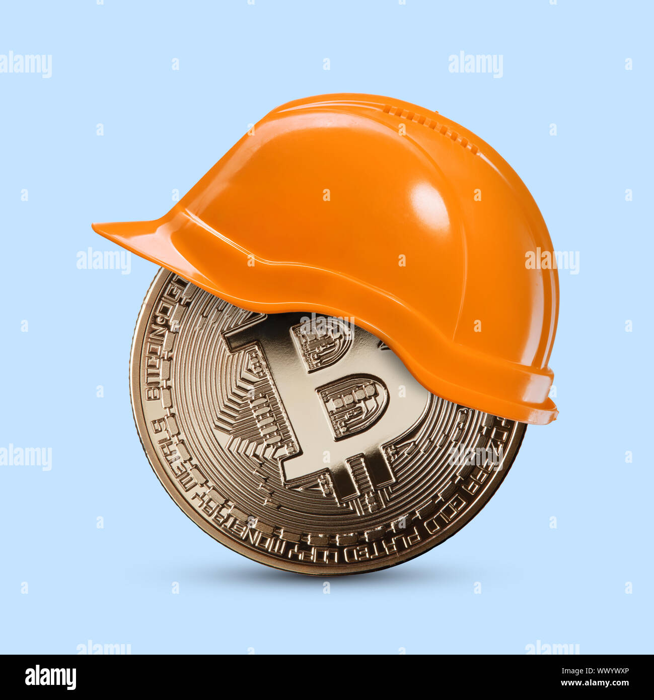 Goldmünze bitcoin in einem Bau Helm auf einem blauen Hintergrund Stockfoto