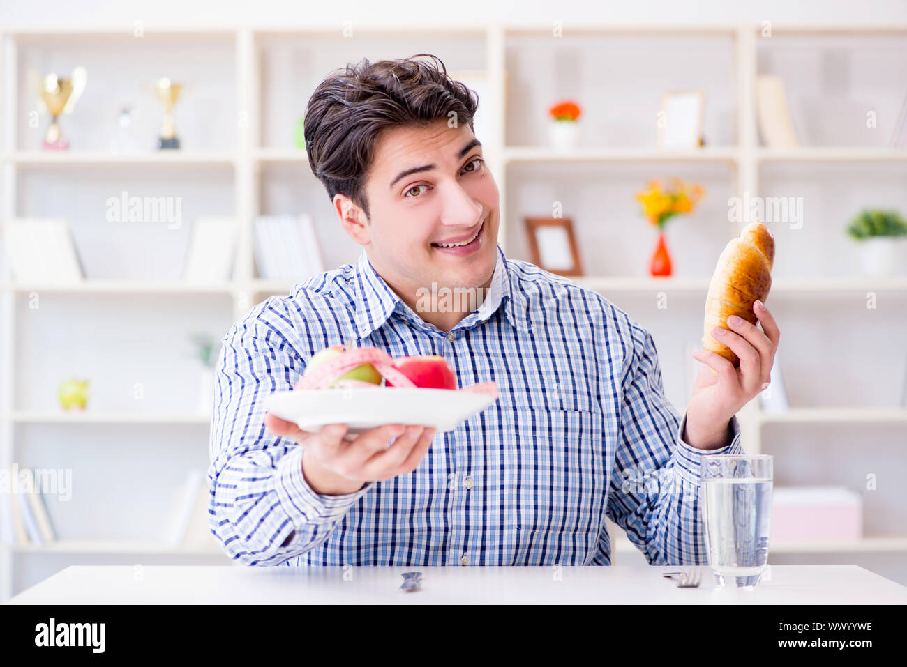 Mann in Dilemma zwischen gesunder Nahrung und Brot nähren con Stockfoto