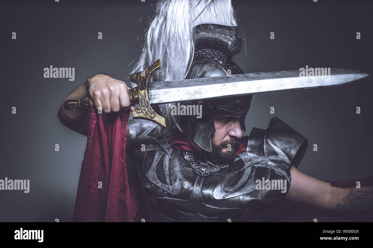 Roman Gladiator, Wrestler und Krieger von Rom mit Helm und roten Mantel,  trägt ein Schwert, Bart und lange Haare Stockfotografie - Alamy