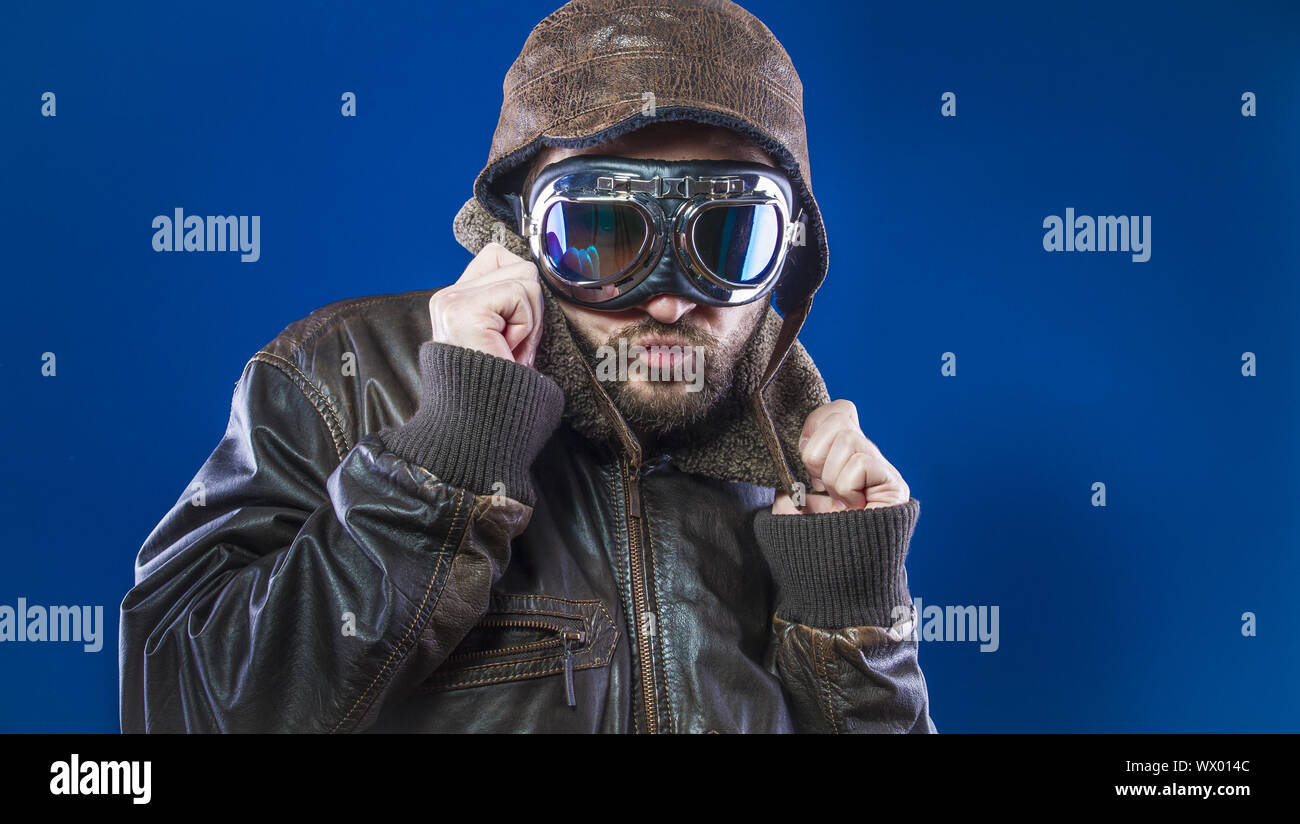 Pilot der 20s mit Sonnenbrille und Vintage aviator Helm. Trägt Lederjacke, Bart und ausdrucksvollen Gesichtern Stockfoto