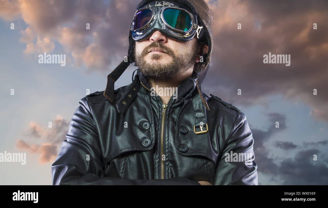 Stolz, Pilot der 20s mit Sonnenbrille und Vintage aviator Helm. Trägt Lederjacke, Bart und ausdrucksvollen Gesichtern Stockfoto