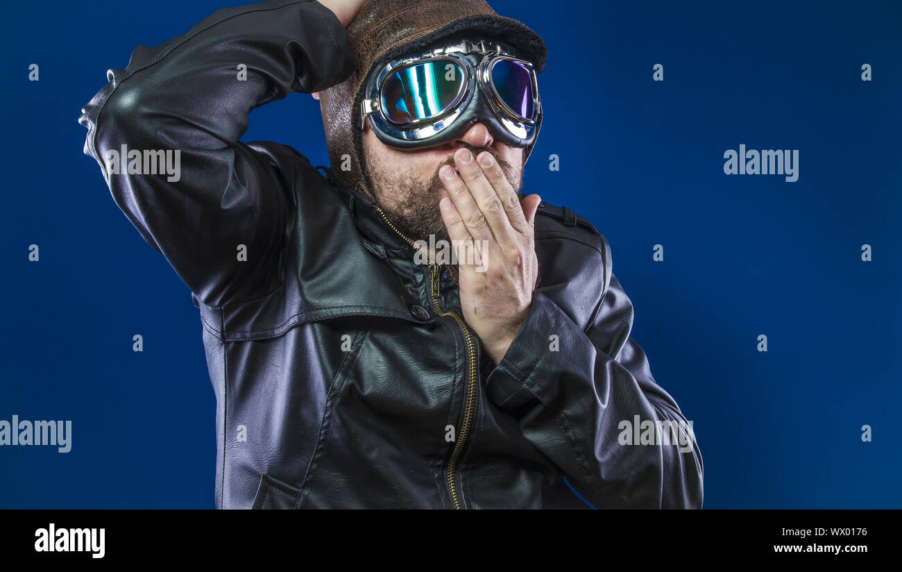 Unfall, Pilot der 20s mit Sonnenbrille und Vintage aviator Helm. Trägt Lederjacke, Bart und ausdrucksvollen Gesichtern Stockfoto