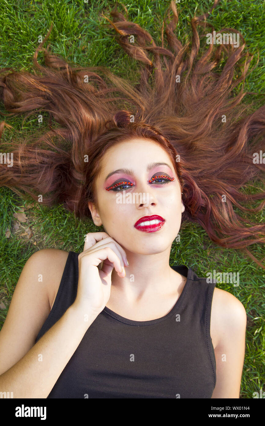 Frühling schöne rothaarige hispanische Mädchen, die auf dem Gras mit heitere und sinnliche schauen Stockfoto