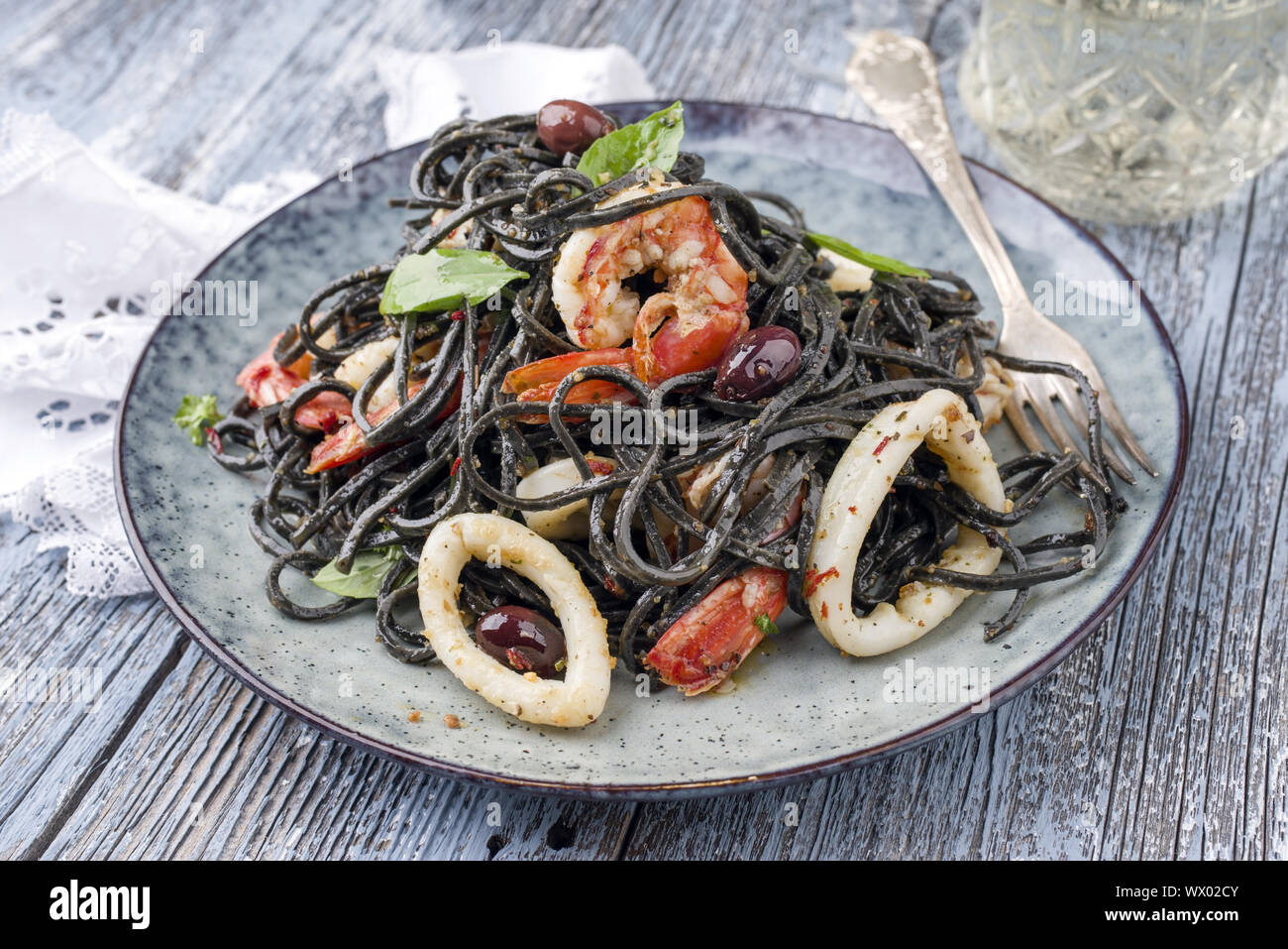 Italienische linguine con Tinta de Tintenfisch und Garnelen mit Oliven als Close-up auf einer Platte Stockfoto