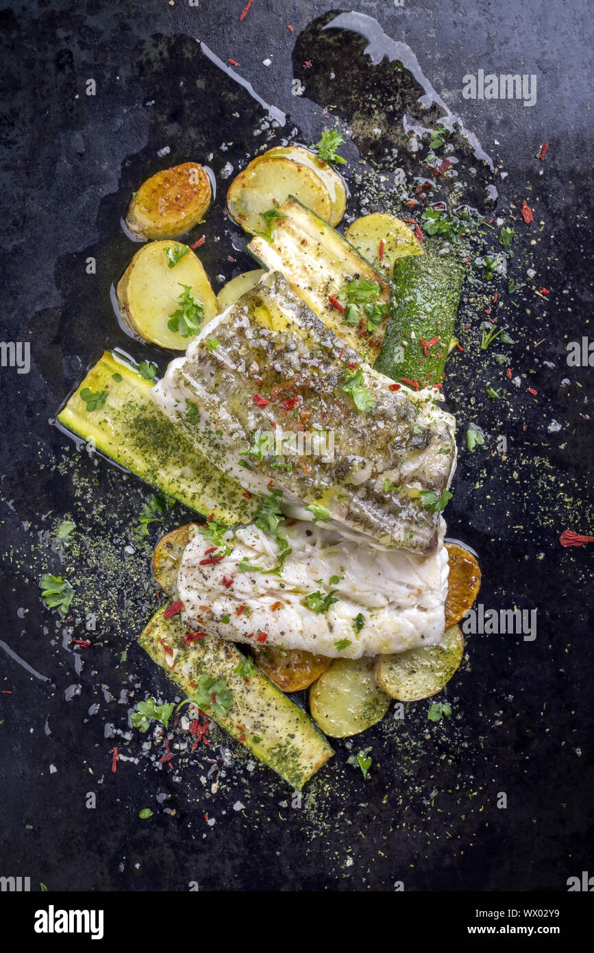 Gebratener Kabeljau Fischfilet mit Gemüse und Kartoffeln als Top - Blick auf die alte Blech Stockfoto