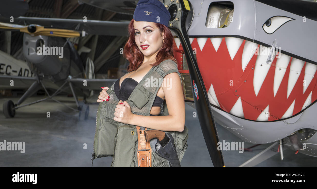 Bomber, rothaarige Frau gekleidet wie ein Soldat neben einem Flugzeug des Zweiten Weltkrieges, Amerikanische pinup im Stil der 40er.Sens Stockfoto