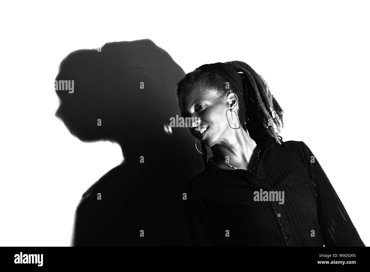 Afroamerikanische Frau mit Dreadlocks gegen eine weiße Wand Stockfoto