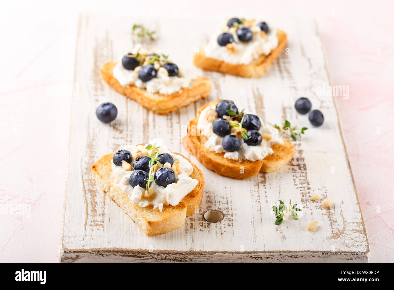 Toast mit frischen Beeren Heidelbeeren Ricotta, Thymian, Honig und Haselnüssen, serviert. Stockfoto