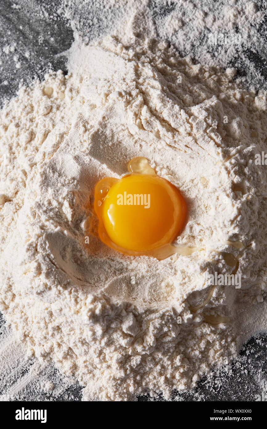 Blick von oben auf ein frisches Eigelb in Mehl auf einem Küchentisch Stockfoto