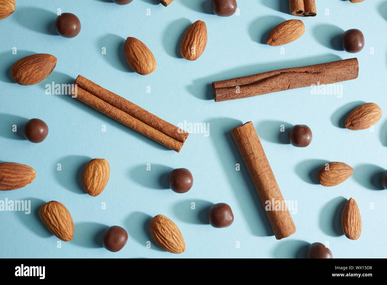 Rohe ungeschälte Mandeln mit einer Zimtstange und Schokolade Kugeln auf einem blauen Hintergrund Stockfoto