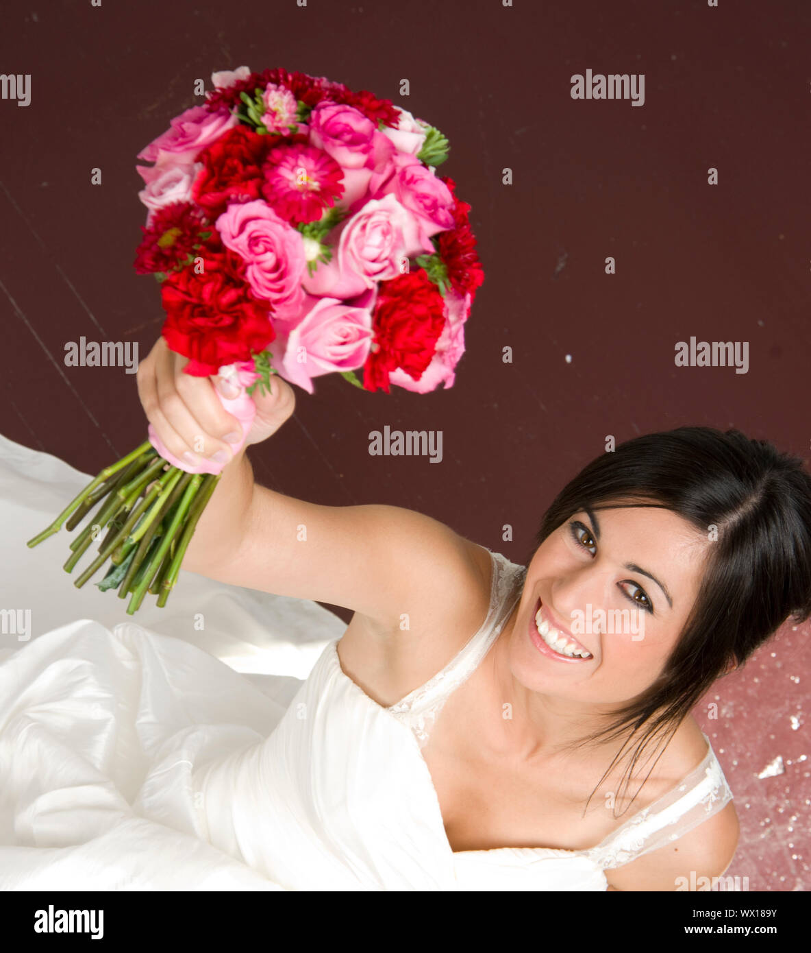 Braut sitzt mit Blumenstrauß Stockfoto