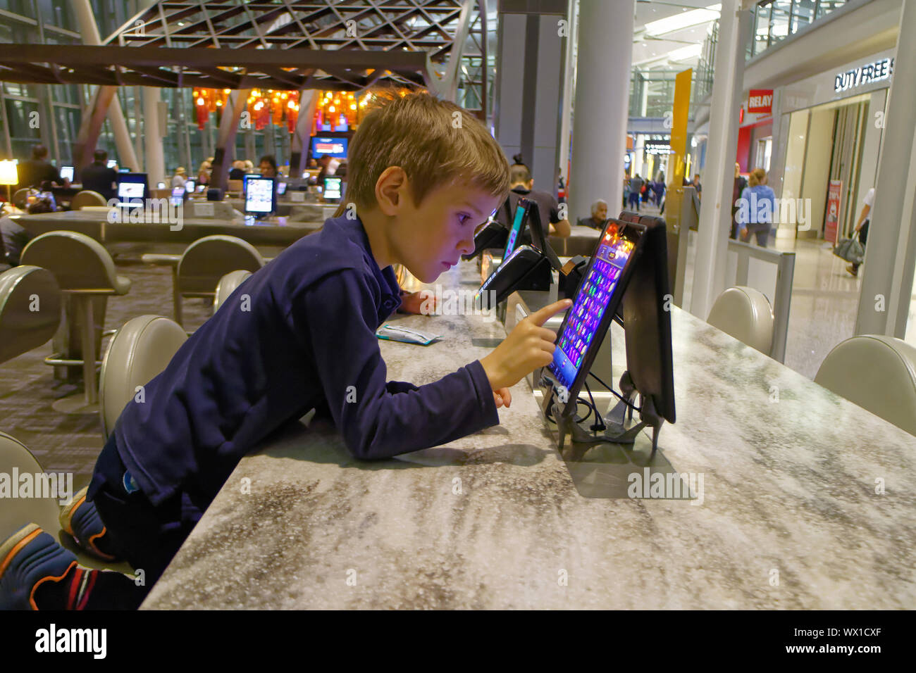 Sie Kinder spielen mit den öffentlichen Gebrauch ipads im Abflugbereich von Toronto Pearson Flughafen Stockfoto