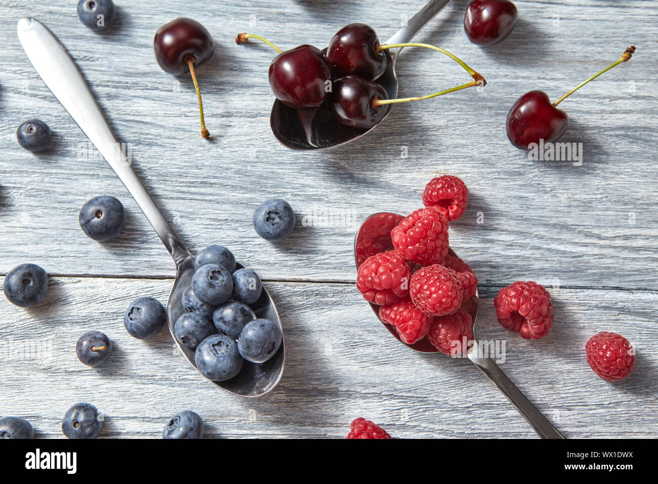 Früchte Muster von frischem Sommer, Blaubeeren, Kirschen, Himbeeren auf grauem Hintergrund. Ansicht von oben. Stockfoto