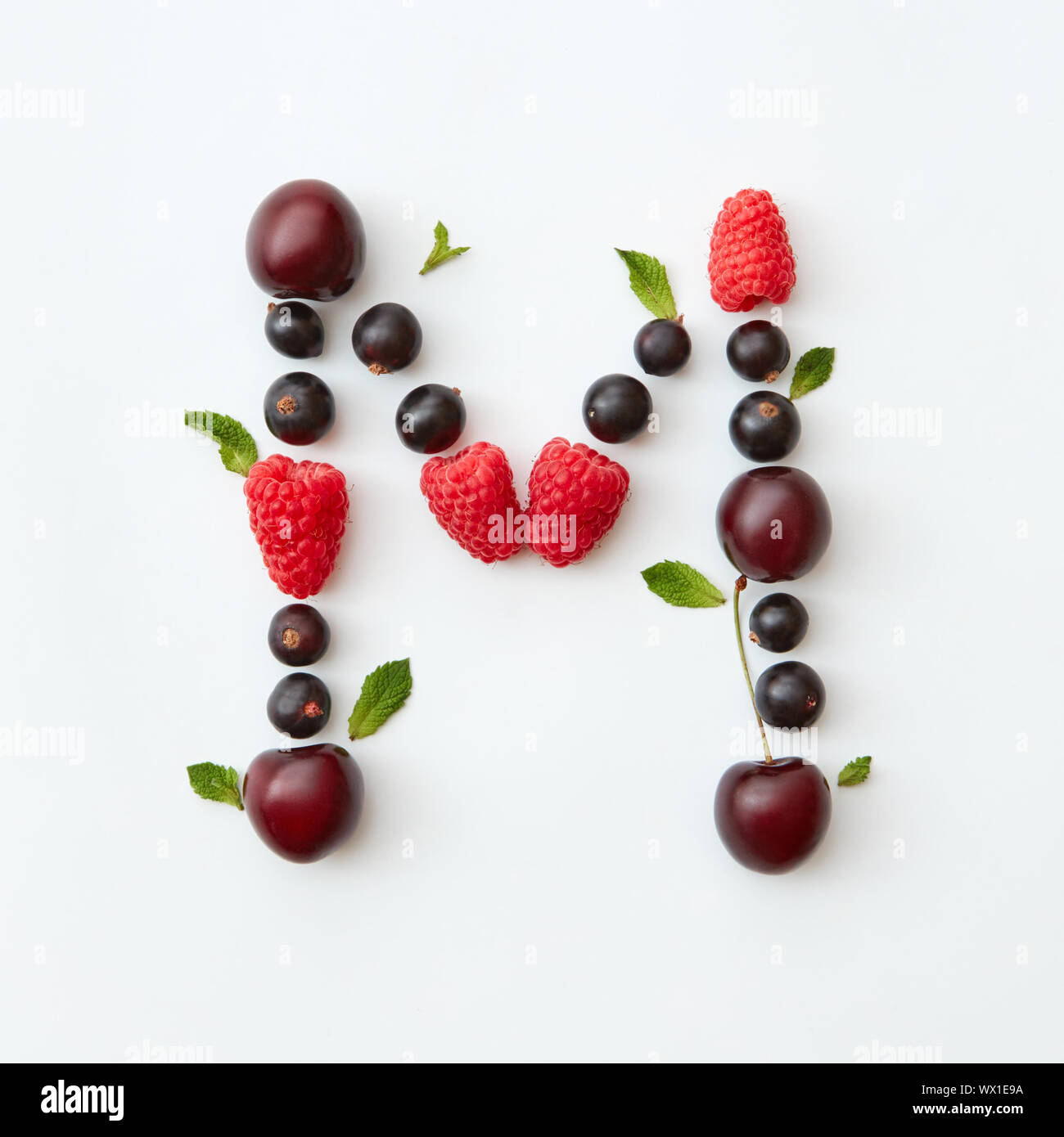 Bunte Muster der Buchstabe M English Alphabet aus natürlichen reife Beeren - schwarze Johannisbeeren, Kirschen, Himbeeren, minzeblatt isoliert Stockfoto