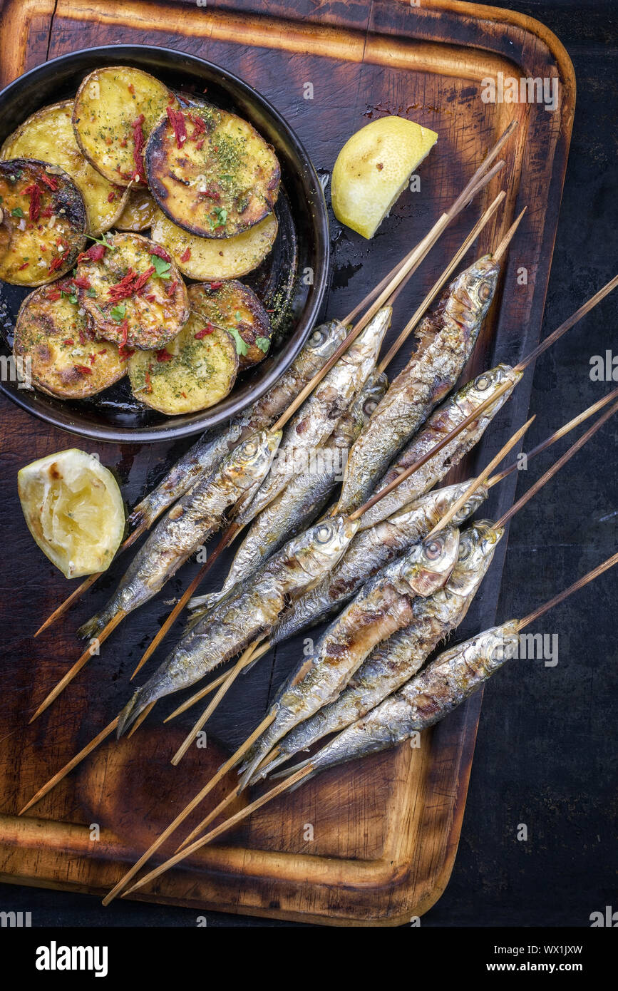 Traditionelle spanische Grill Sardinen auf Holz Spieß mit Pommes als Draufsicht auf einem Schneidebrett Stockfoto