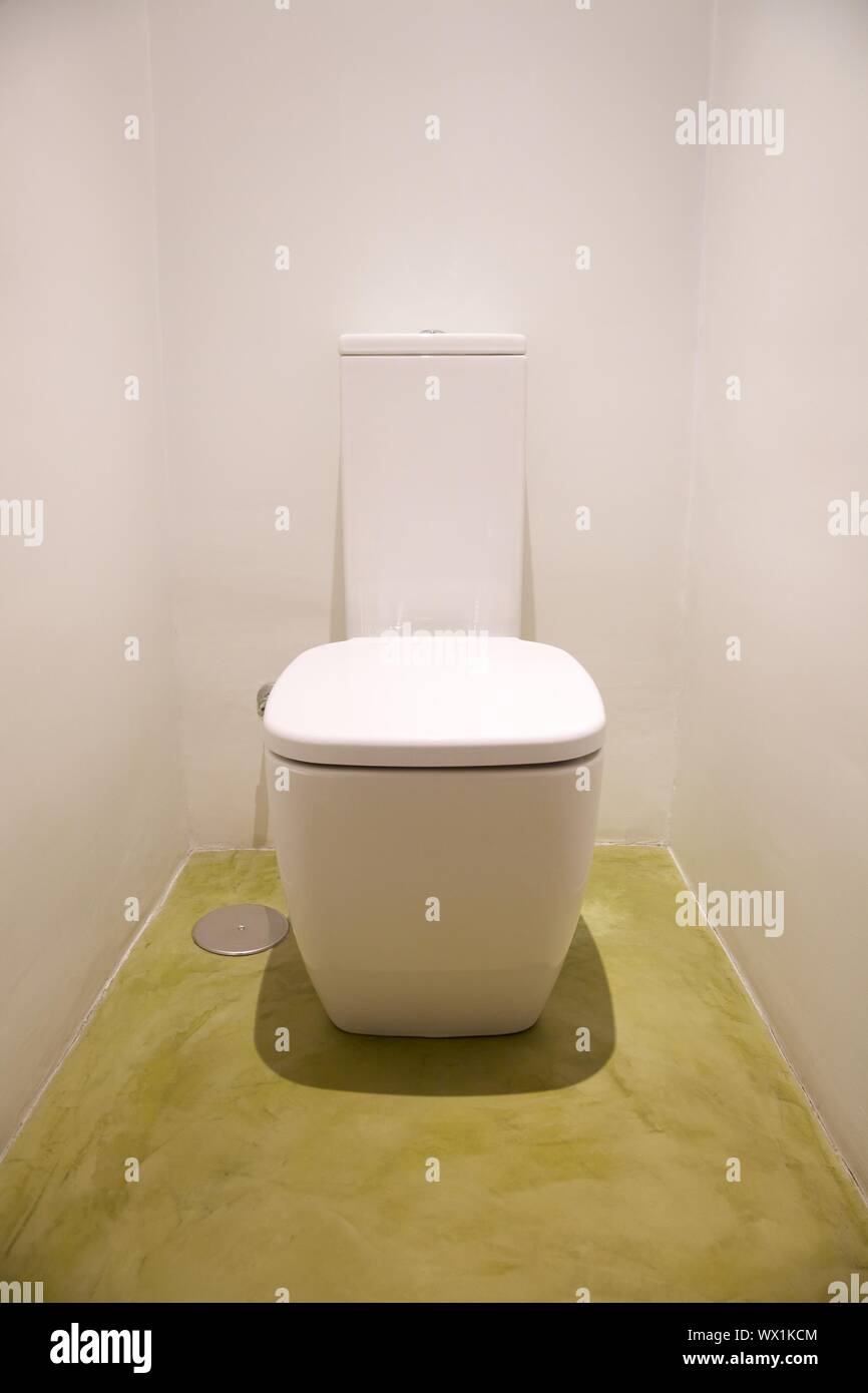 Toilette im weißen Badezimmer mit grünen Boden Stockfoto