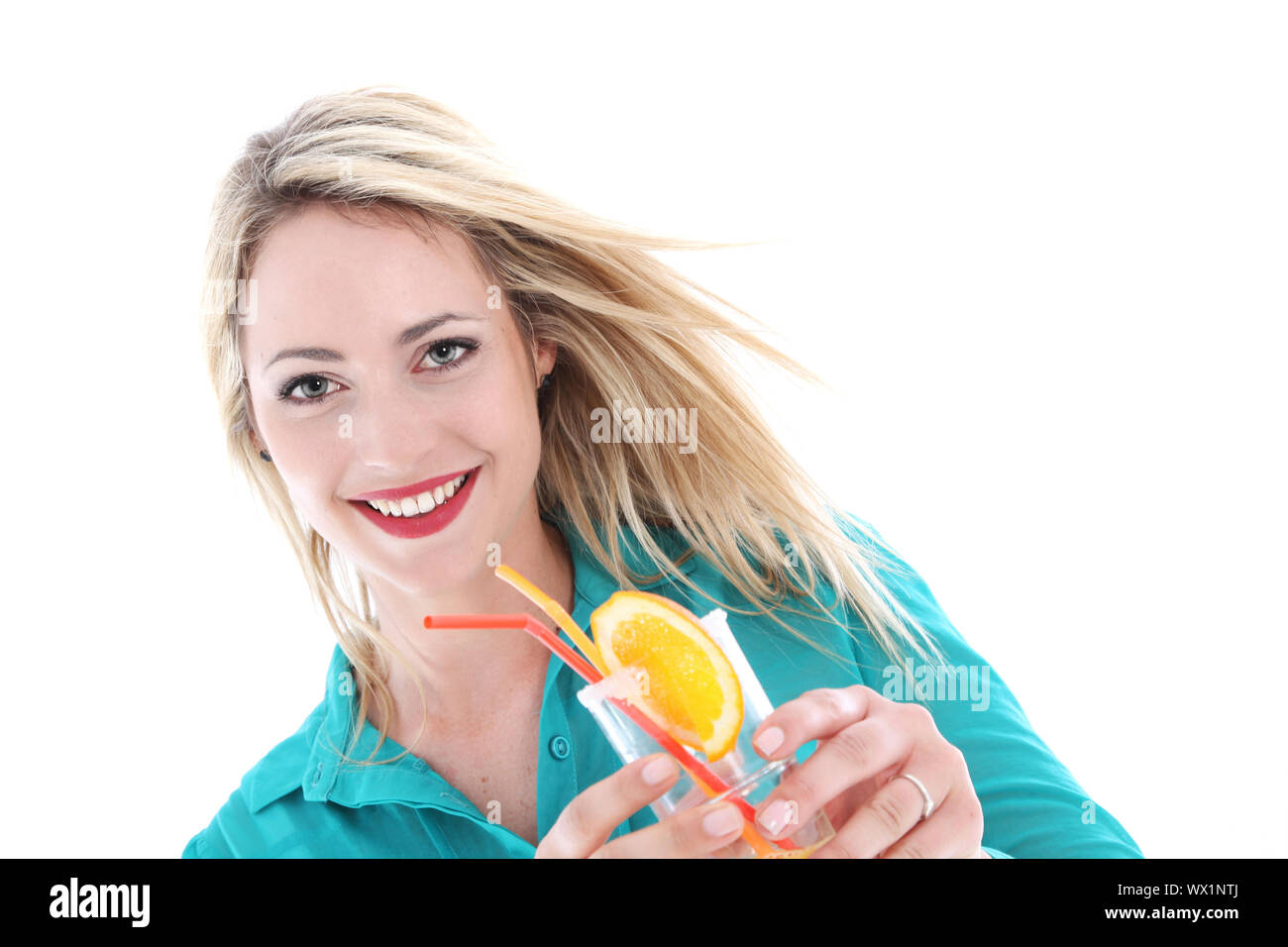 Schöne unbeschwerte Frau mit dem Wind im Haar und ein freudiges Lächeln mit einem Glas Cocktail auf einer tropischen Urlaub Stockfoto