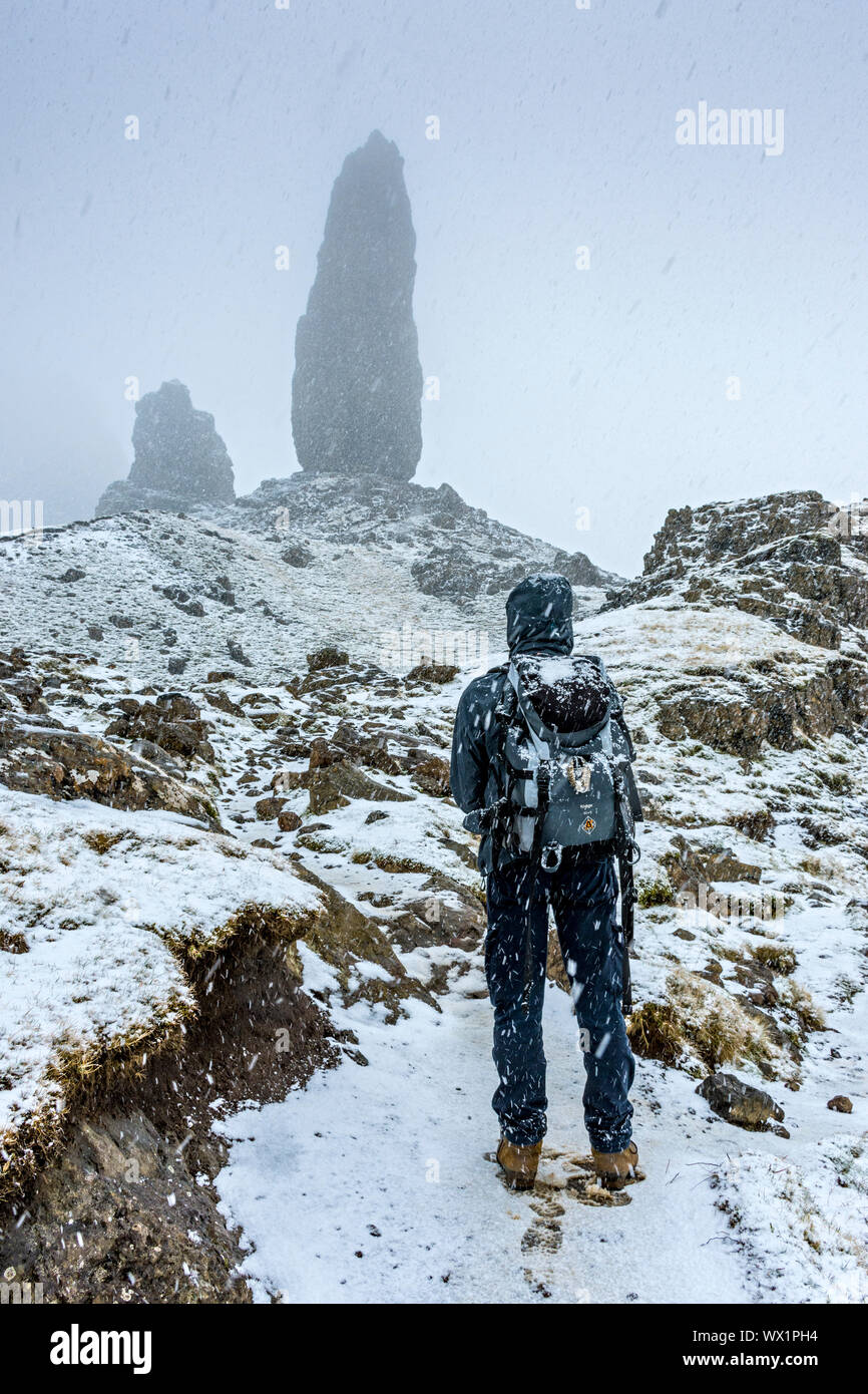 Ein Wanderer nähert sich der Alte Mann von Storr rock Pinnacle in einem schweren Schnee Dusche. Die Storr, Trotternish, Isle of Skye, Schottland, Großbritannien Stockfoto