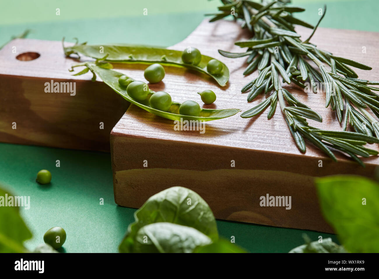 Grüne organische sauber Gemüse - Rosmarin, Hülsen, Erbsen, Bohnen, Spinat auf ein Holzbrett auf der Grünen. Stockfoto