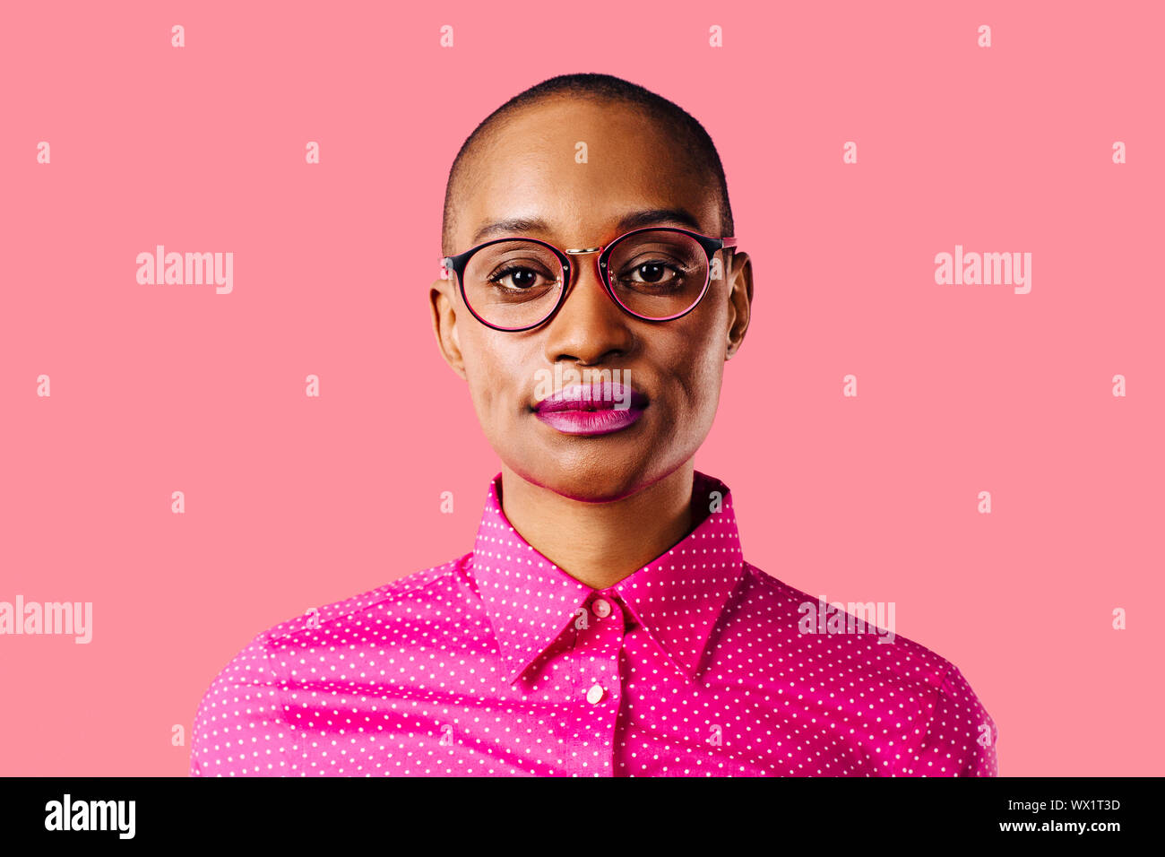 Porträt eines intelligenten jungen Frau in rosa Hemd und Brille, auf Pink Studio Hintergrund isoliert Stockfoto