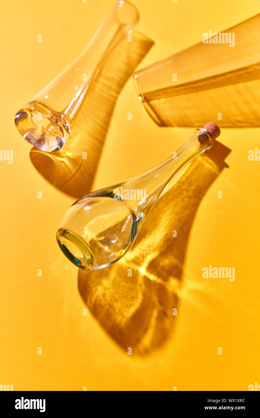 Drei Flaschen leer auf gelbem Papier Hintergrund mit weichen Schatten und Reflexionen. Stockfoto