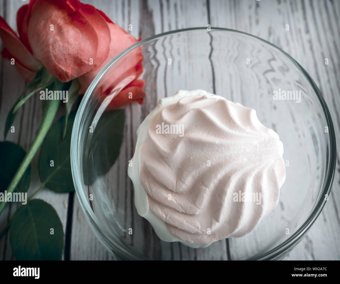 Ein Marshmallow in einem Glas Vase neben einer Rose. Stockfoto