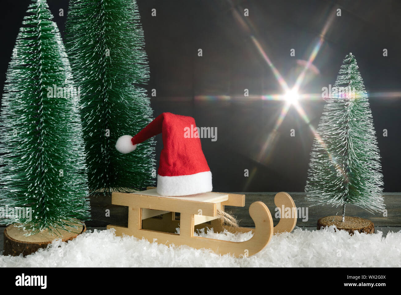 Weihnachtsdekoration mit einem roten Santa Claus hat auf einem Schlitten neben Tannen und leichte flare Stockfoto